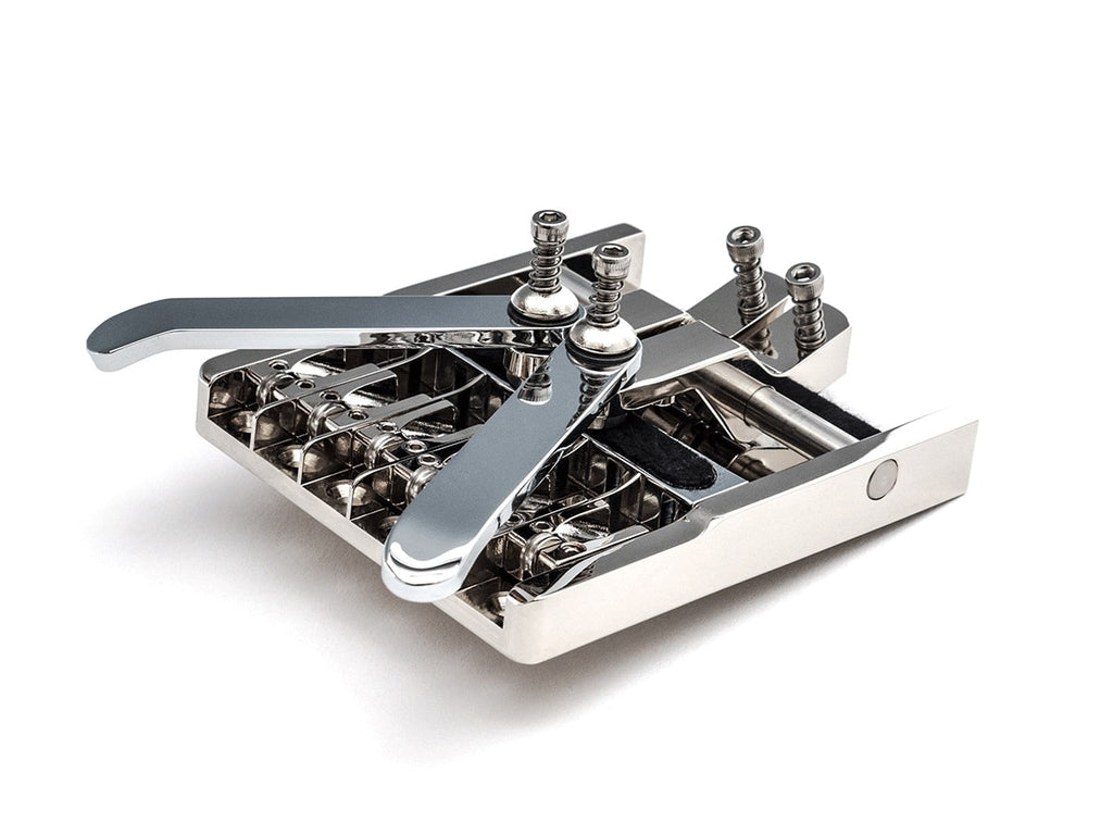 Close-up image of a metal guitar bridge component with screws and adjustable saddles on a white background.