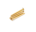 Four gold-colored metal screws with flat heads and Phillips drive arranged on a white background.