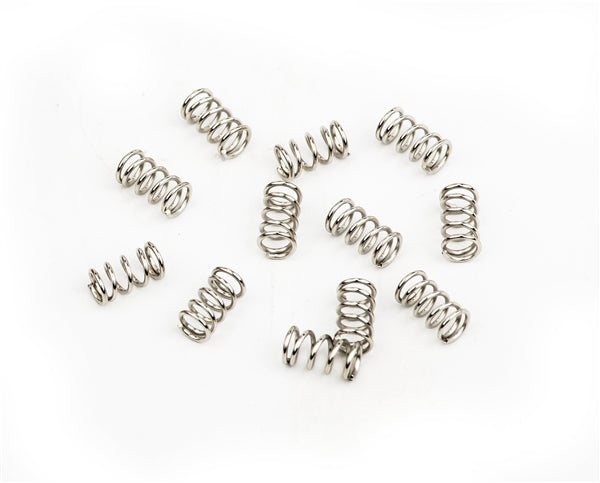 Twelve small metallic compression springs scattered on a white background.