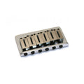 Close-up of a metallic guitar bridge assembly with six adjustable saddles and screws on a white background.