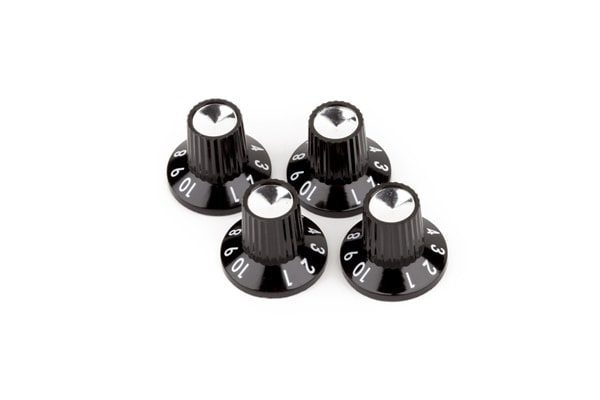 Four black amplifier knobs with silver tops and white numbering around the base arranged on white background.
