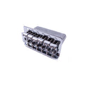 Silver metal guitar tremolo bridge with six string saddles viewed from an angle on white background.