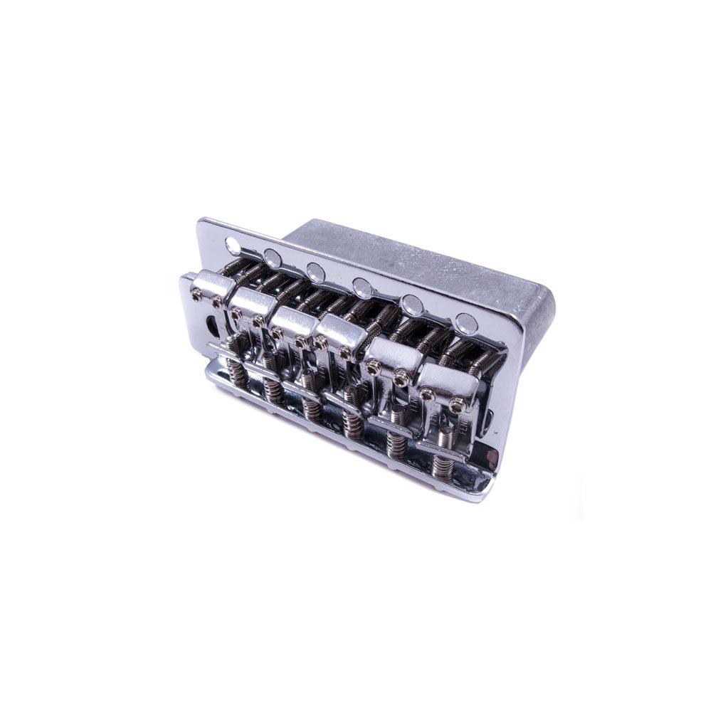 Silver metal guitar tremolo bridge with six string saddles viewed from an angle on white background.