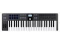 Black MIDI keyboard controller with 49 keys, 8 pads, multiple knobs and faders, and a small display in the center.