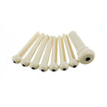 Seven ivory bridge pins with black dots arranged on a white background.