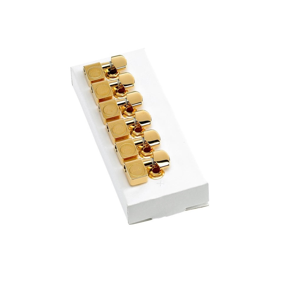 Set of six gold-colored tuning machines with Fender logo displayed on a white tray.