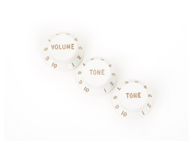 Three white rotary control knobs labeled Volume and Tone with gold numbering from 1 to 10.