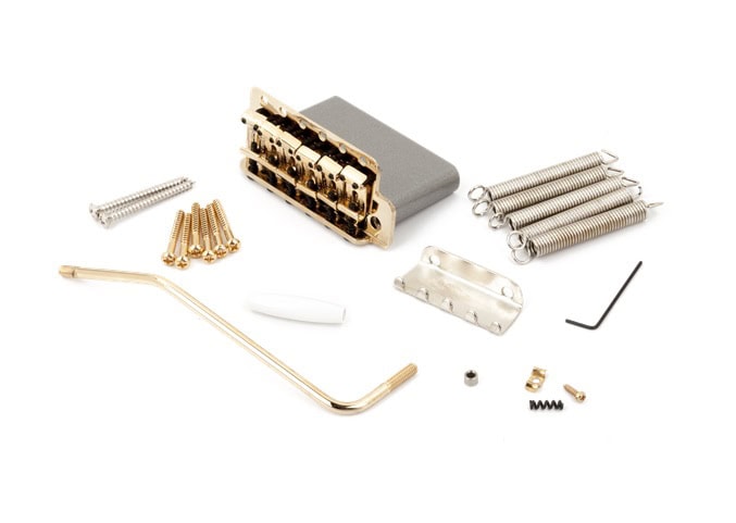 Gold-colored guitar tremolo bridge assembly kit with springs, screws, tremolo arm, and small parts on a white background.