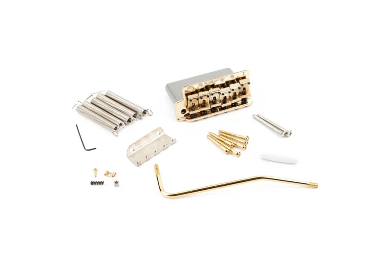 Gold-colored guitar tremolo bridge assembly with springs, screws, tremolo arm, and small parts on white background.