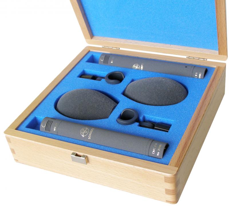 Open wooden box with two small black microphones, two foam windshields, and two microphone clips in blue foam padding