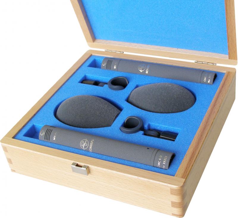 Open wooden case with two microphones, foam windshields, and accessories set in custom blue foam.
