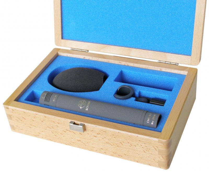 Gray cylindrical microphone labeled CMC 6 U with accessories in a wooden box with blue foam interior.
