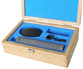 Microphone and accessories neatly arranged in blue foam inside a wooden case with open lid.