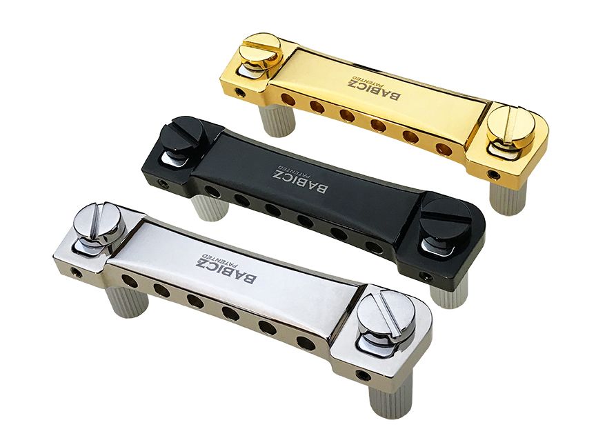 Three metal guitar tailpieces in gold, black, and silver with screw knobs and holes for string attachment.