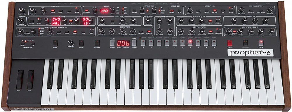 Top view of a black keyboard synthesizer with wooden side panels labeled prophet~6 and multiple control knobs and buttons.