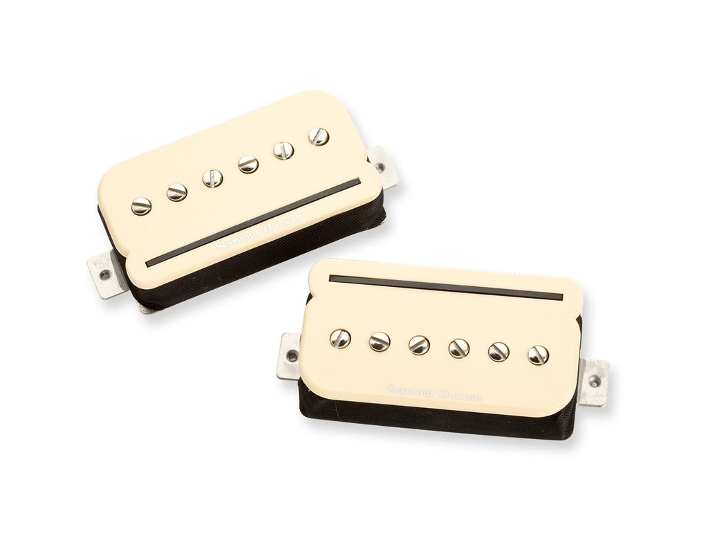 Two cream-colored guitar pickups with metal screws and black bases on a white background.