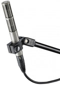 Silver and black studio microphone with a metal grille mounted in a black holder attached to a black boom arm, connected via XLR cable.
