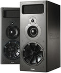 A tall, upright rectangular PMC MB2S passive studio monitor in a dark cabinet, with a three-way driver array on the front baffle: a large low-frequency cone driver, a smaller midrange dome, and a tweeter above it.