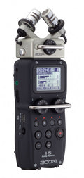 Handheld audio recorder with dual built-in microphones, LCD screen, rotary knobs, and various control buttons.