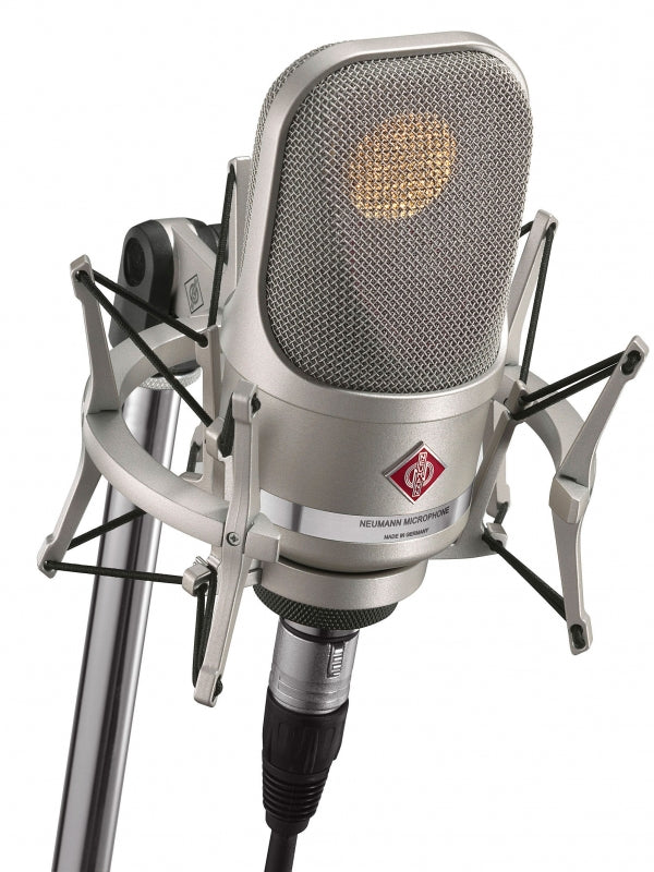 Silver Neumann microphone mounted in a shock mount on a stand with an XLR cable connected.