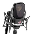 Black Neumann studio microphone with shock mount and XLR connector shown up close.