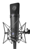 Black studio microphone with shock mount and visible Neumann logo on the body and grille.