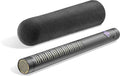 Black shotgun microphone with a foam windscreen lying beside it on a white surface.