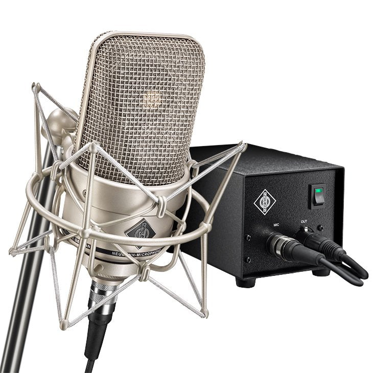 Silver microphone mounted in a shock mount connected to a black box with cables and a green toggle switch.