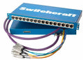 Blue patchbay unit with multiple circular connectors and attached multi-colored cables with metal connectors.