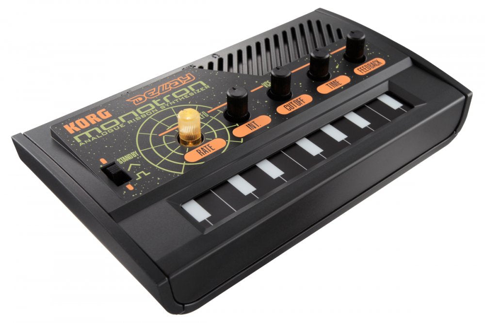 Black Korg analogue ribbon synthesizer with white keys and orange-labeled control knobs and slider shown at an angle.