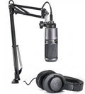 Black Audio-Technica microphone on adjustable arm with USB connector and black headphones beside it.