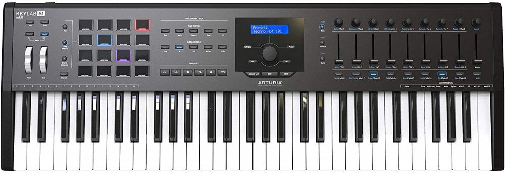 Black MIDI controller keyboard with 61 keys, pads, knobs, buttons, and a central display screen showing a preset.