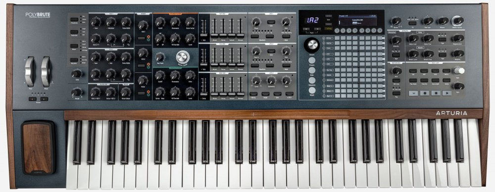 Top view of a black and gray keyboard synthesizer with knobs, faders, buttons, joystick, and a small screen display.