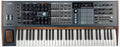 Top view of a black and gray keyboard synthesizer with knobs, faders, buttons, joystick, and a small screen display.