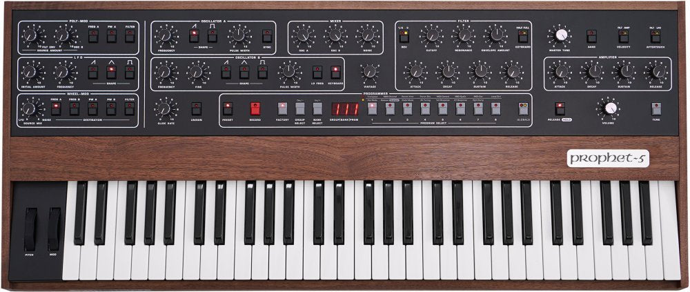 Front view of a Prophet-5 synthesizer with knobs, switches, buttons, a keyboard, and wooden side panels.
