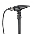 Black Neumann microphone with a conical head mounted on a stand with attached cable.