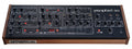 Black desktop synthesizer module with wood side panels and various knobs, buttons, and sliders labeled prophet-10.