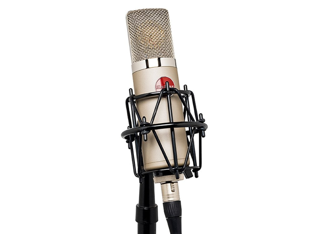 Beige condenser microphone with silver grille in black shock mount attached to microphone stand with XLR cable connected
