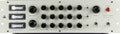 Front panel of an audio processing unit with multiple knobs, toggle switches, three analog meters, and power switch.