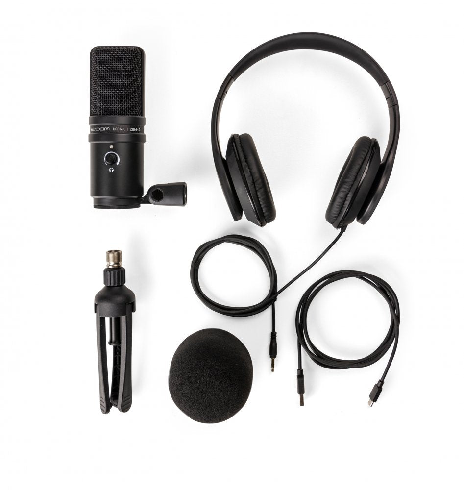 Black USB microphone with headphones, tripod stand, windshield foam, and cables laid out on a white background.