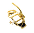 Gold-colored vibrato tailpiece with attached lever and four screws laid beside it.