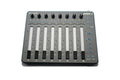 Top-down view of a ZAXCOM Aria-8 audio mixer with eight channel sliders, knobs, and labeled buttons on a gray surface.