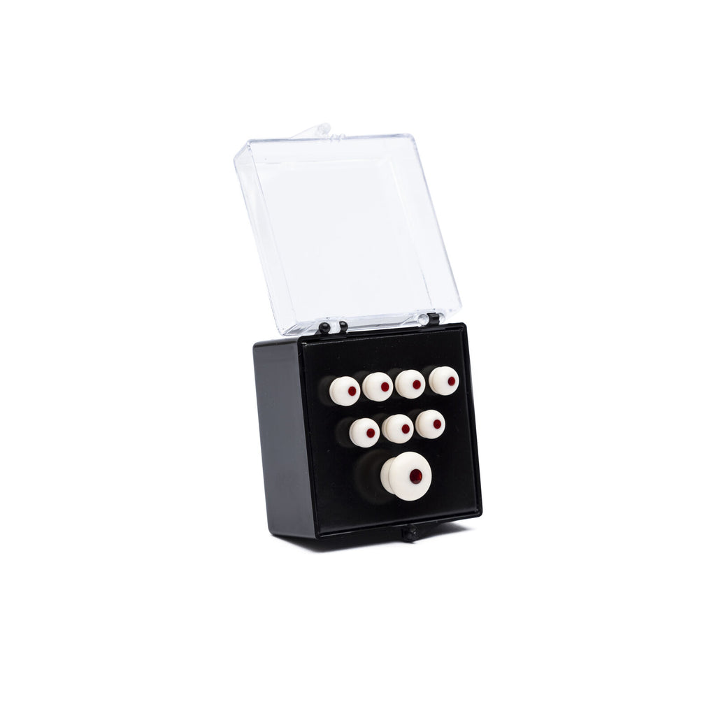Clear-lidded black plastic box containing a set of small white round pieces with red centers arranged in rows.