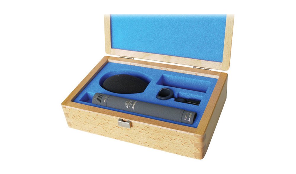 A microphone set in a wooden box with blue foam padding including a microphone body, windscreen, and clip.