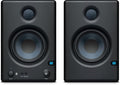Front view of a pair of black studio monitor speakers with visible drivers, volume knob, power switch, and audio input jacks.