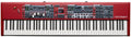 Red synthesizer keyboard with multiple control panels, sliders, knobs, buttons, and a display screen.
