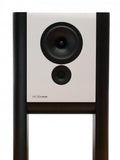 Grimm Audio LS1a active studio monitor in white lacquer: a wide, shallow two-way cabinet with a woofer and tweeter, suspended between two cylindrical legs that form its integrated floor stand.