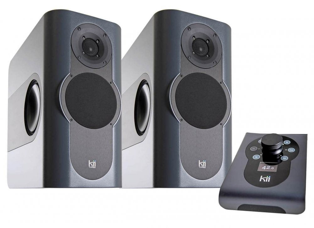 Two dark grey speakers and a black remote control with a display and control buttons.