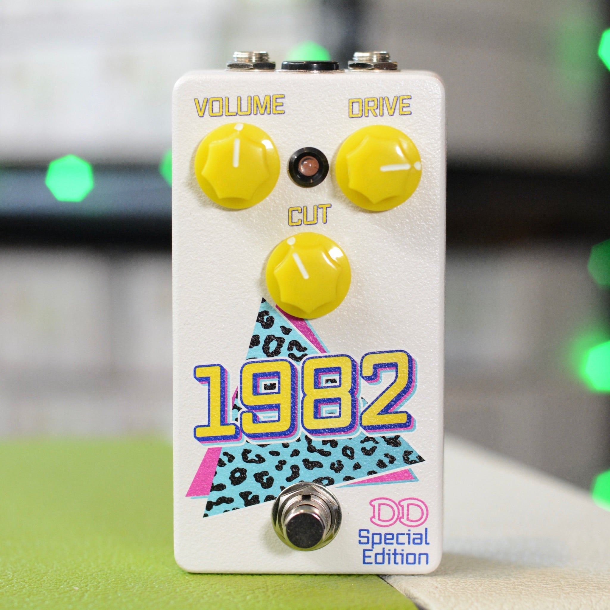 White guitar effects pedal with three yellow knobs and colorful 1982 graphic on front.