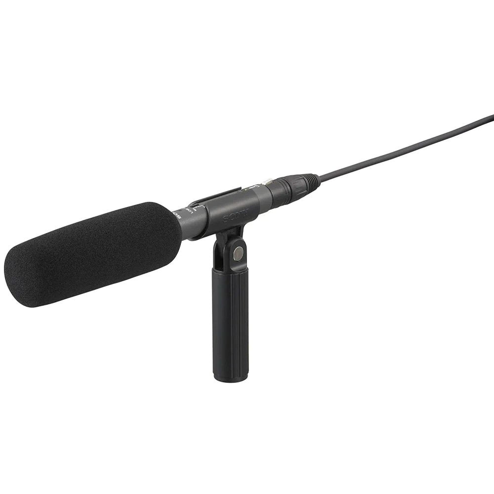 Black shotgun microphone with foam windscreen, handheld mount, and attached cable with cylindrical connector.